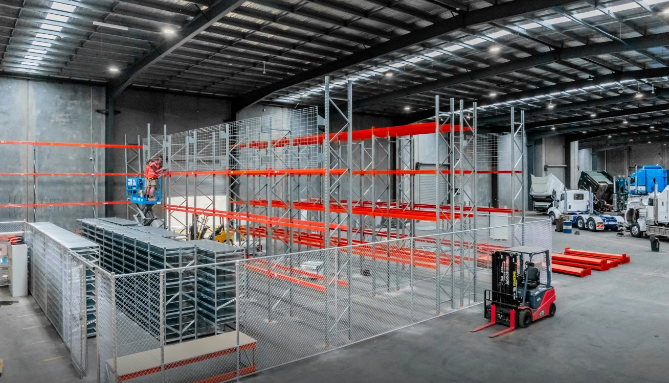 Warehouse racking installation with scissor lift and technicians assembling storage system